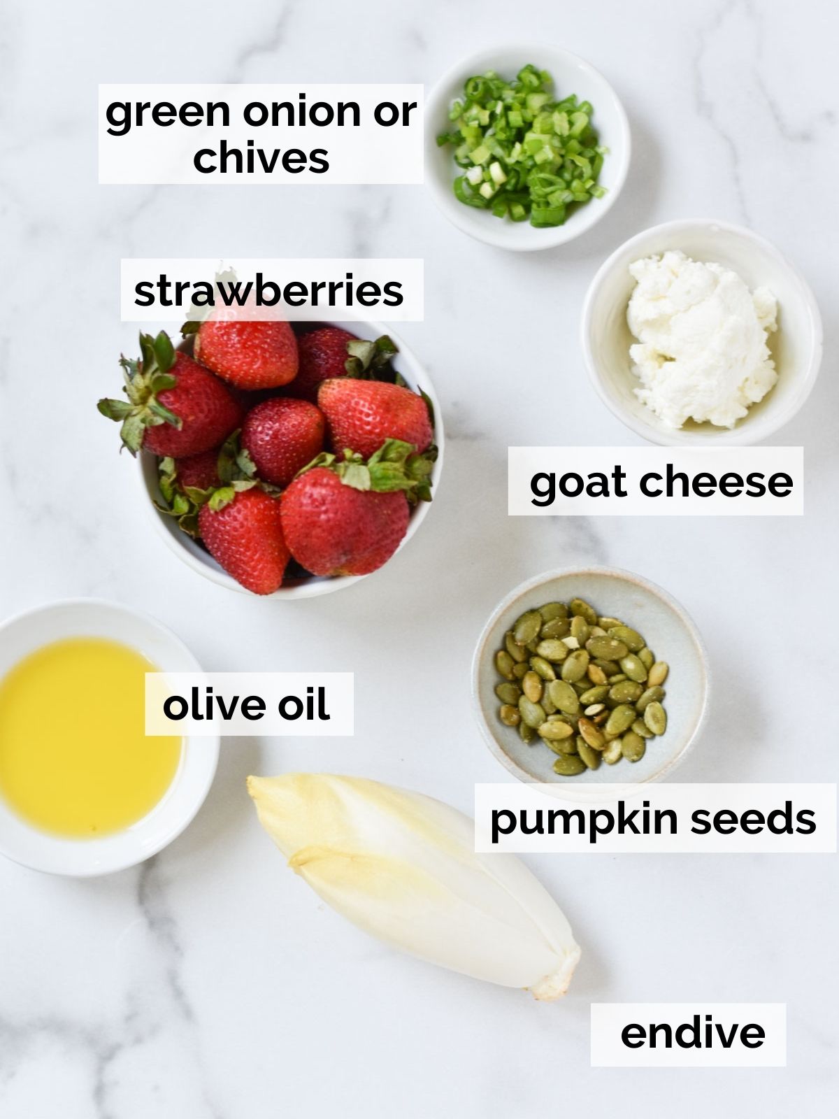 Endive, strawberries, and vinaigrette on a table.