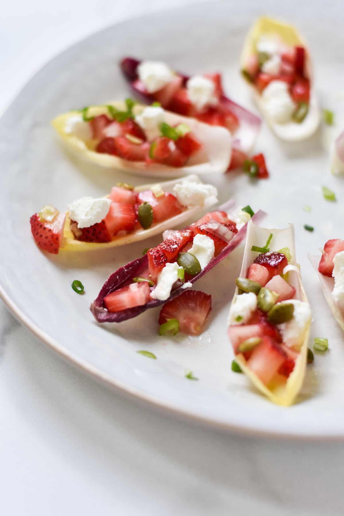 Stuffed endive appetizers topped with goat cheese.