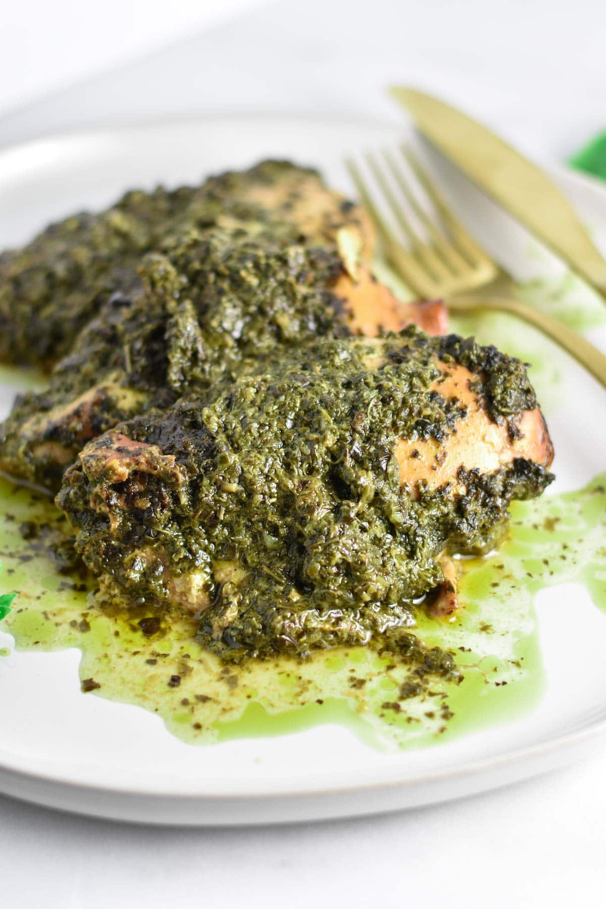 Cooked chicken topped with a pesto sauce.
