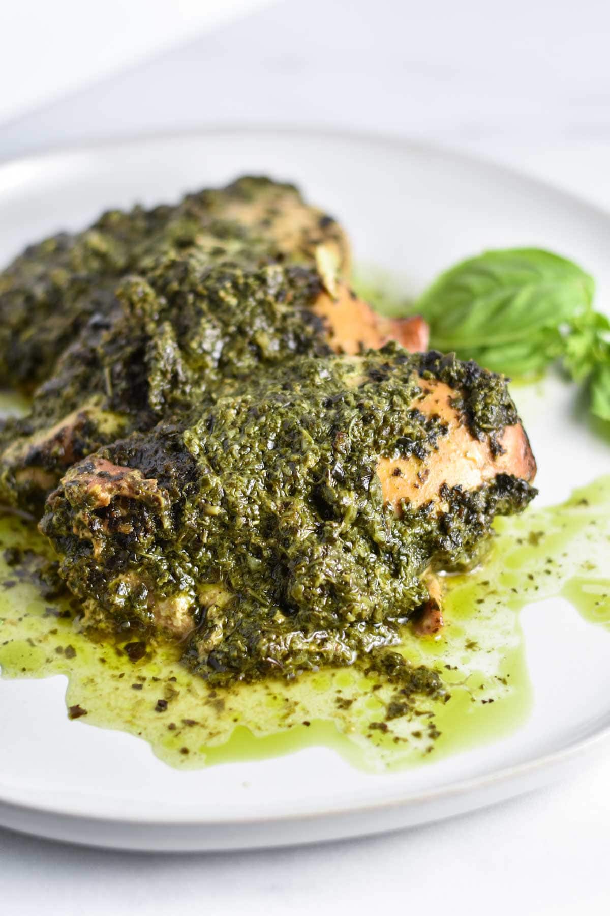 Crockpot pesto chicken on a plate with basil.