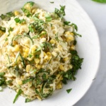 Creamy corn pasta in a white bowl topped with basil.