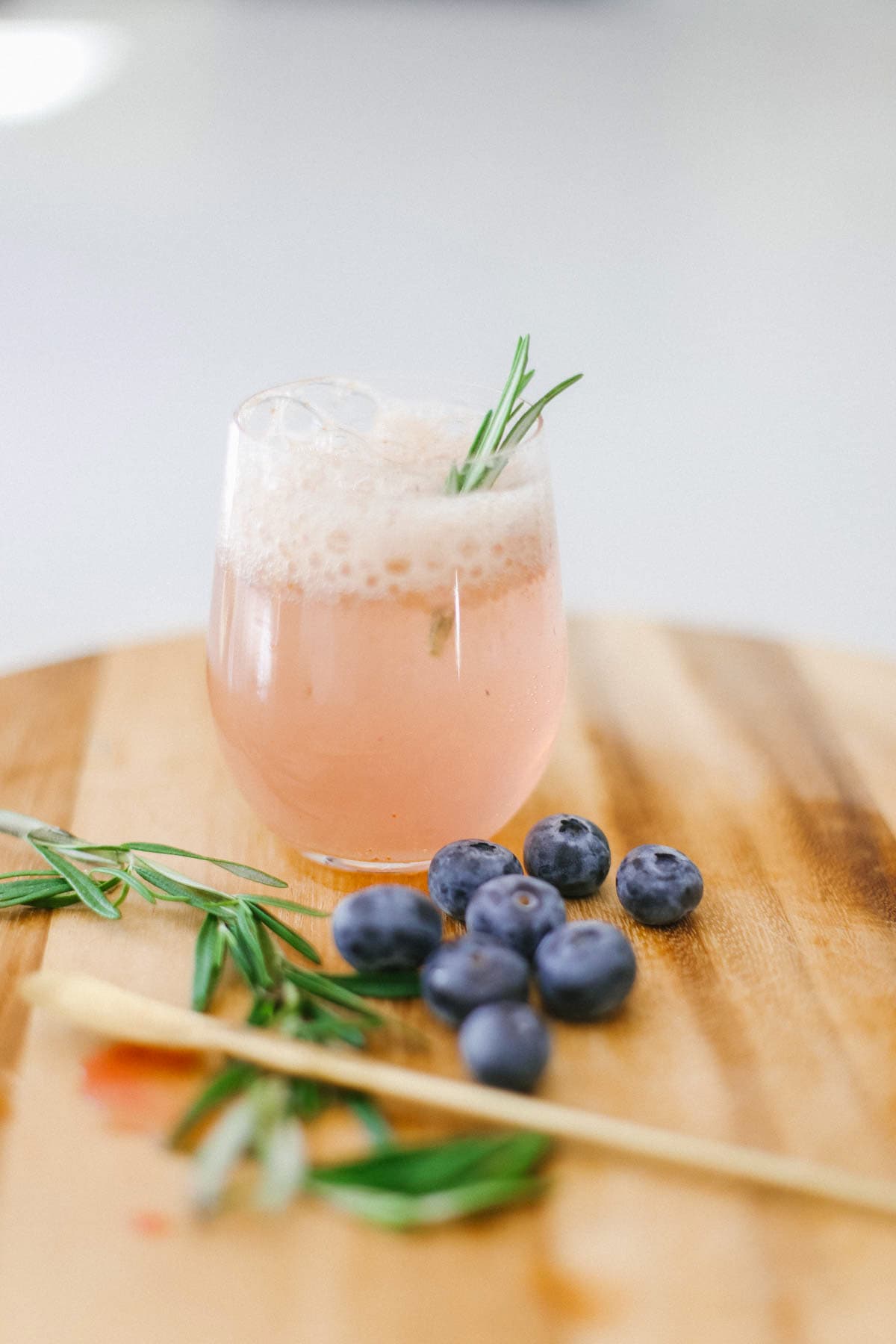A mocktail with blueberries and herbs with a cocktail stirrer.