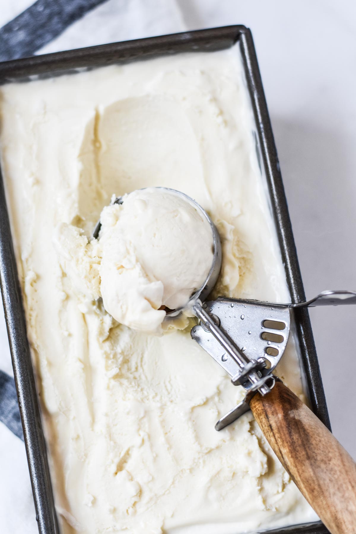 Scooping homemade ice cream in a container.