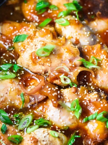 Apricot chicken in a slow cooker topped with green onion.