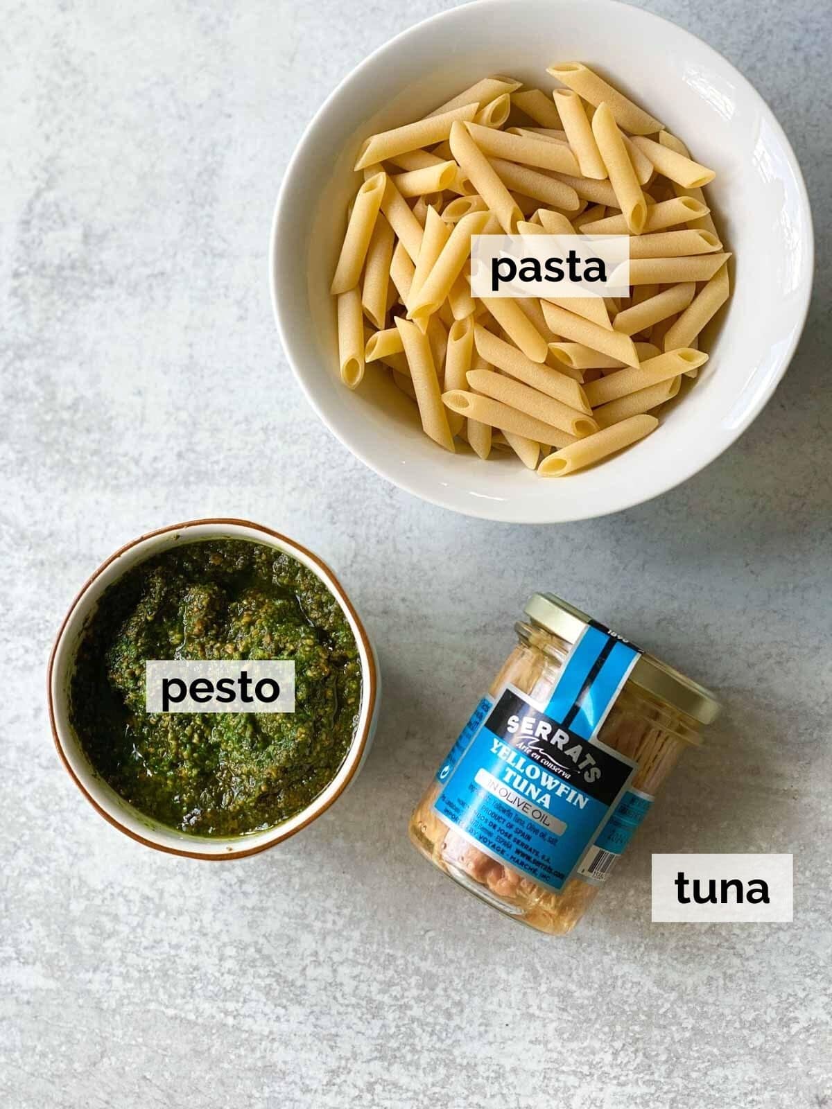 Pasta, pesto, and tuna on a table.