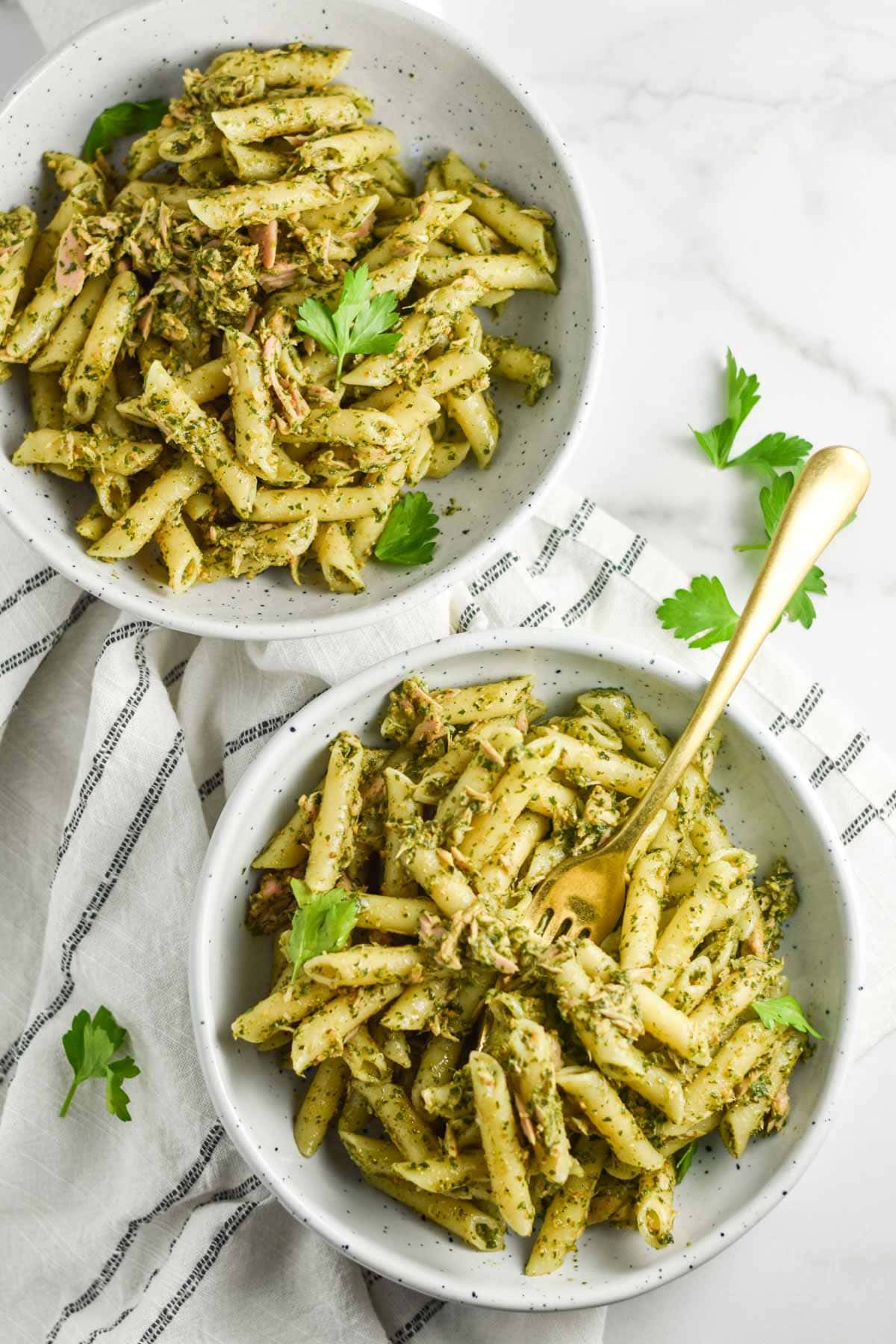 Two bowls of pasta with a fork dipping in.