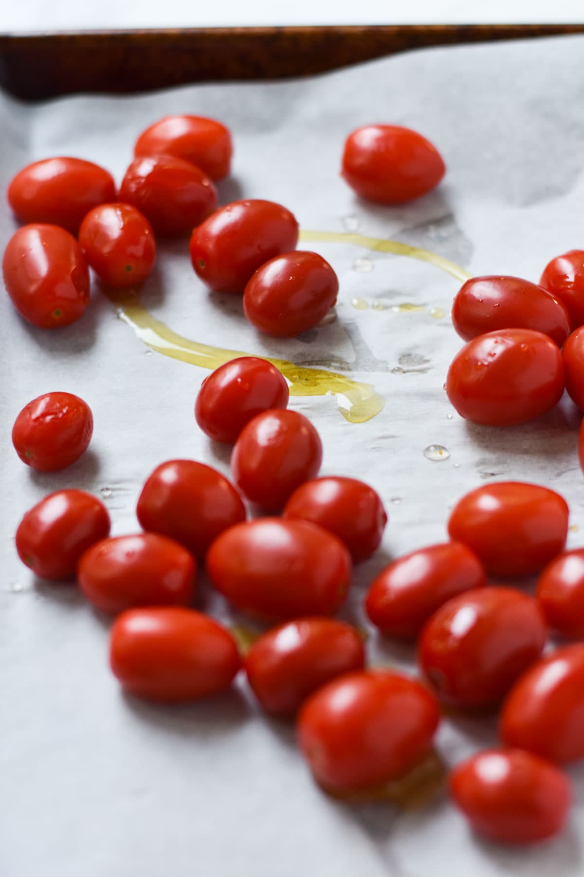 Cherry tomatoes and olive oil on a baking sheet.