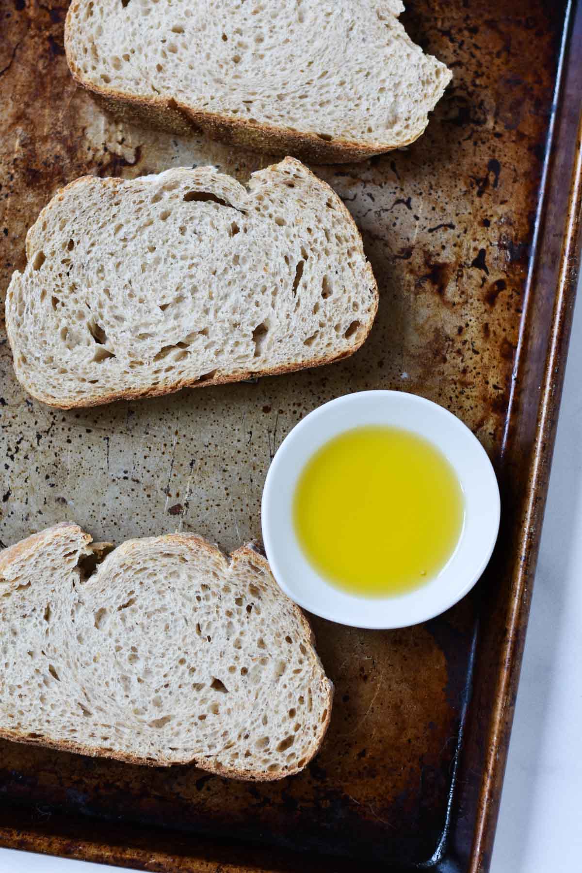Fresh bread on a baking sheet with olive oil.