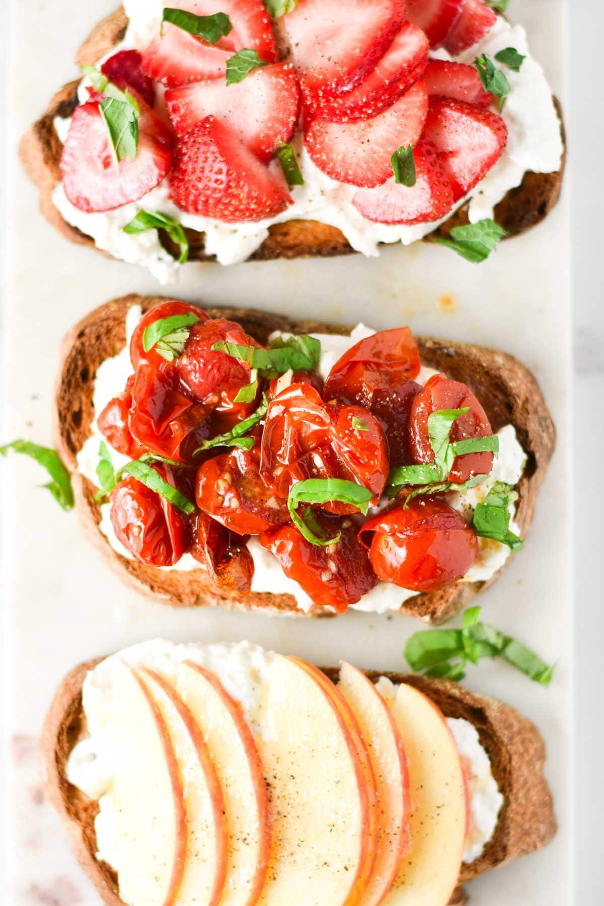 Roasted tomatoes, apples, and strawberries on top of toasts.
