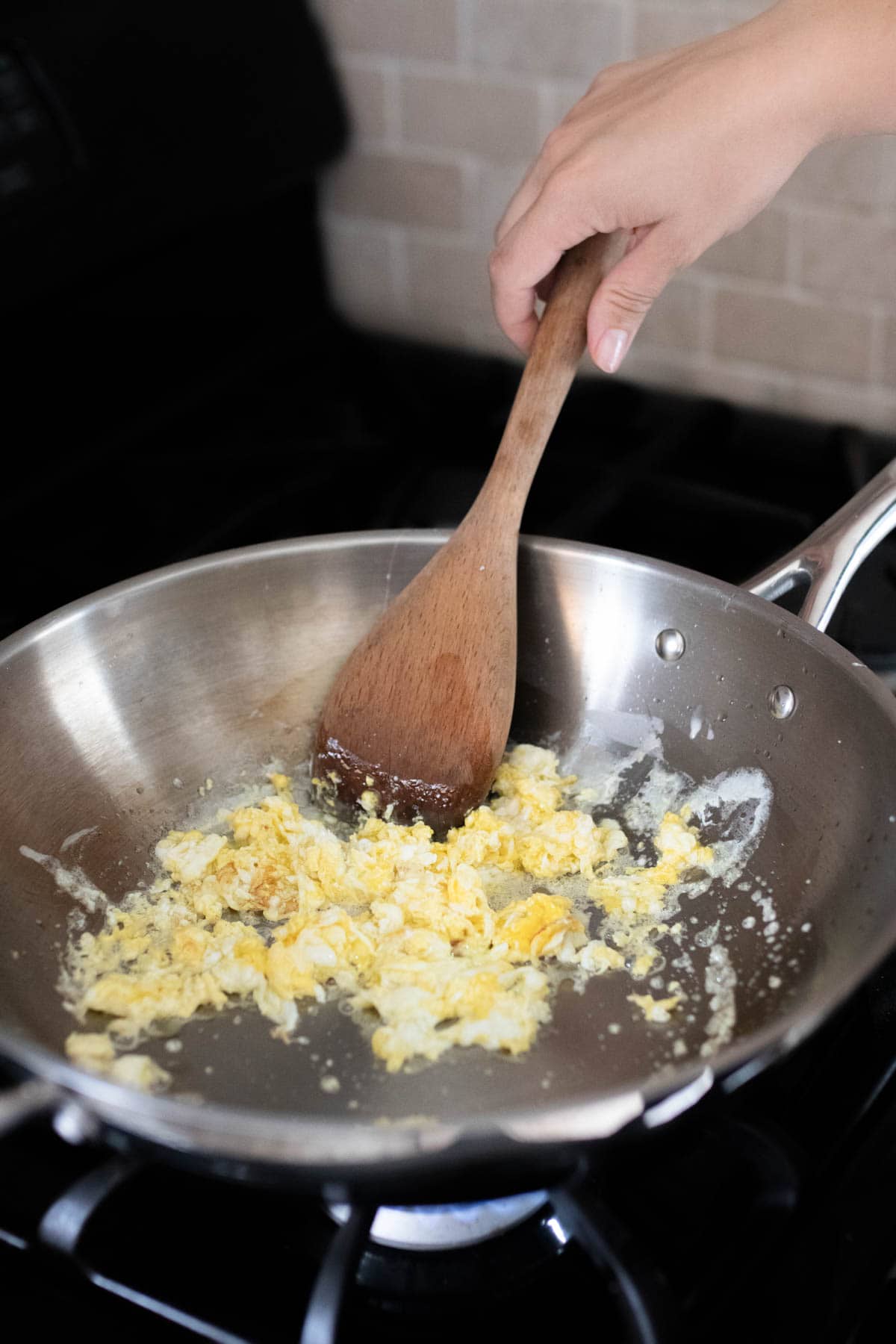 Cooking scrambled eggs with a wood spoon.
