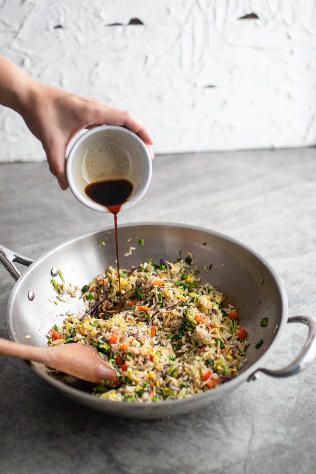 Pouring sauce into cooked fried rice.