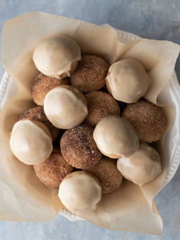 Baked donut holes in a bowl with parchment paper.