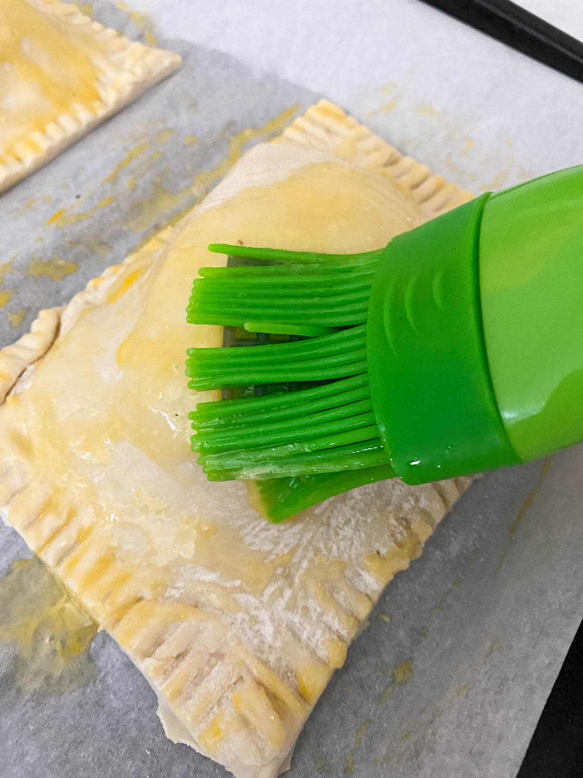 Brushing puff pastry pockets with egg. 
