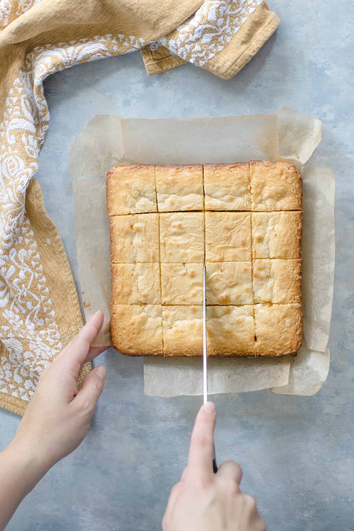 Cutting the blondies into squares with a knife.