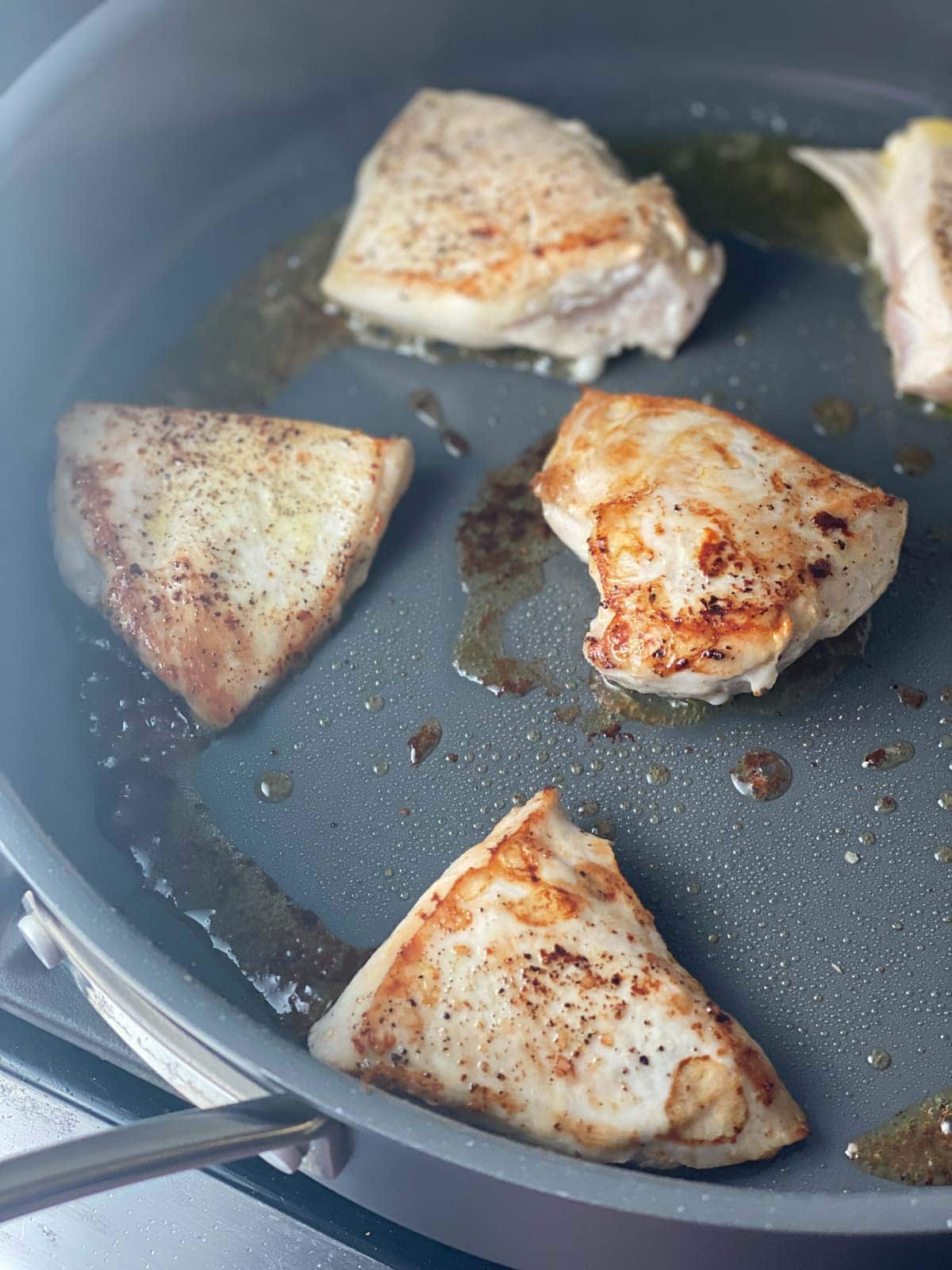 Chicken breasts being seared in a pan. 