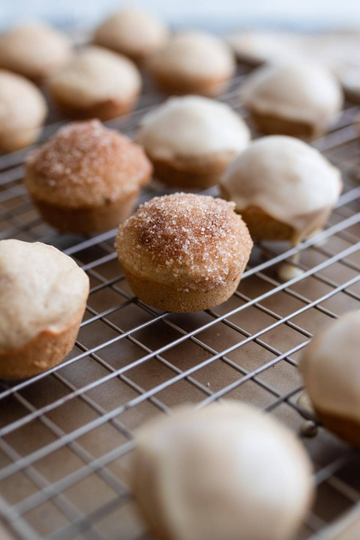Donut holes on a baking rack after being coated with cinnamon sugar and glaze.