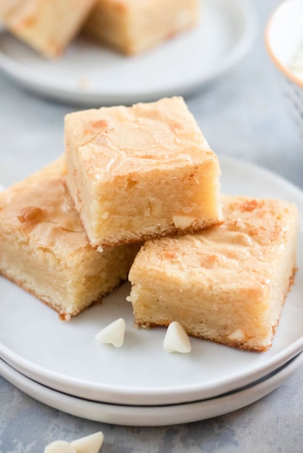 White chocolate brownies on a plate next to white morsels.