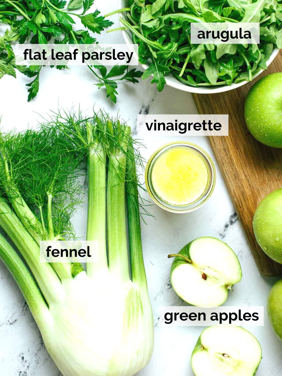 Fennel, apples, parsley, arugula, and vinaigrette on a table.