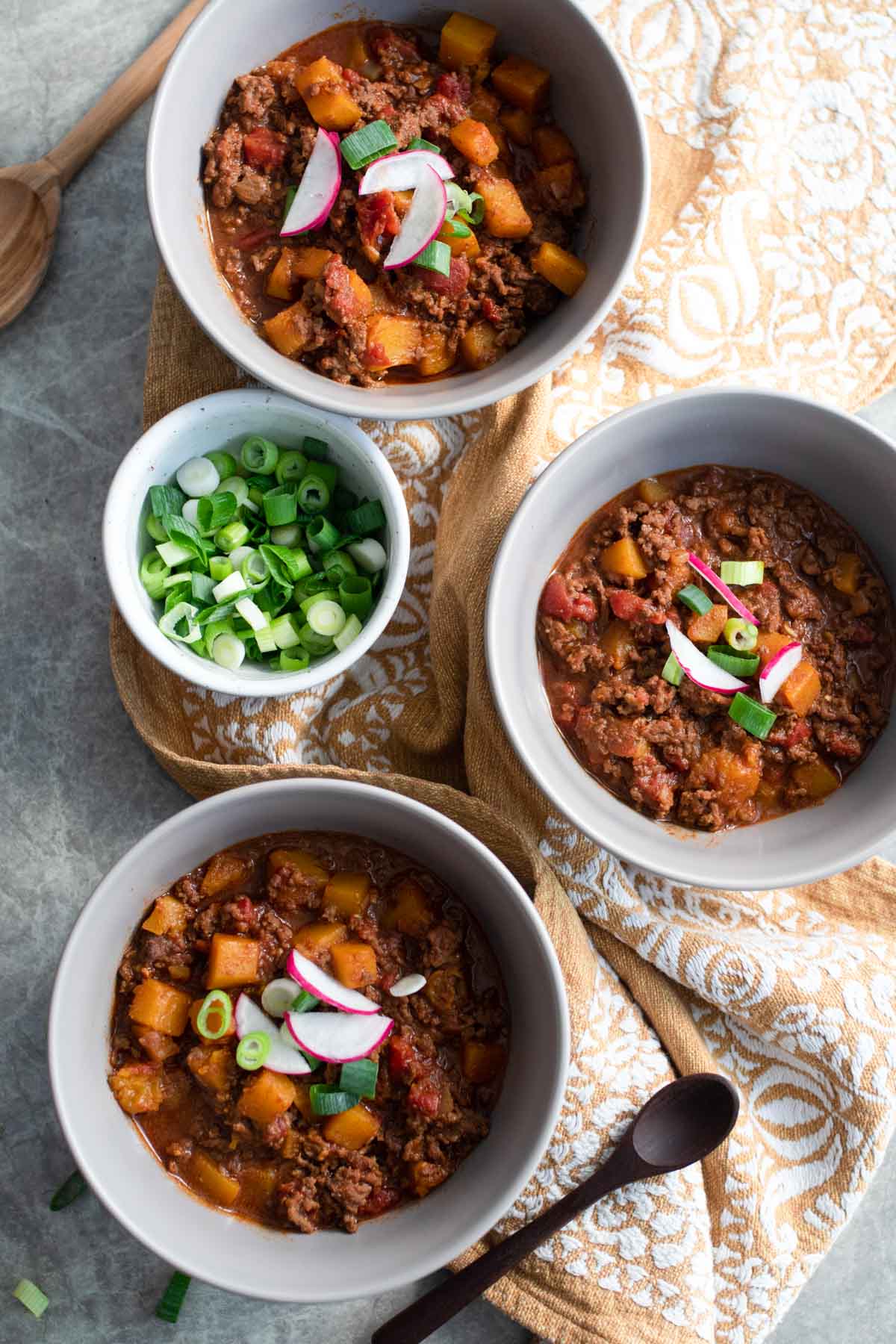 Three bowls of chili with green onions.