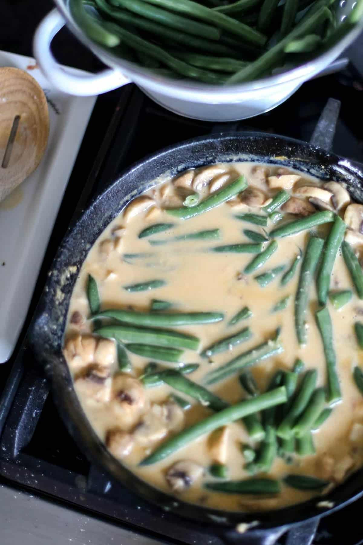 Adding the cooked fresh green beans to the mushroom sauce.