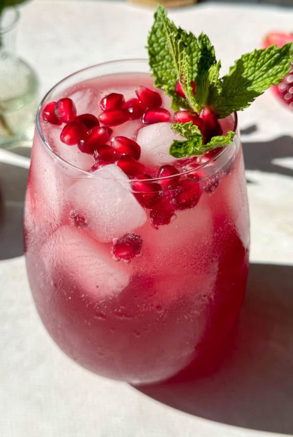 Pomegranate mocktail with pomegranate arils and mint on top.