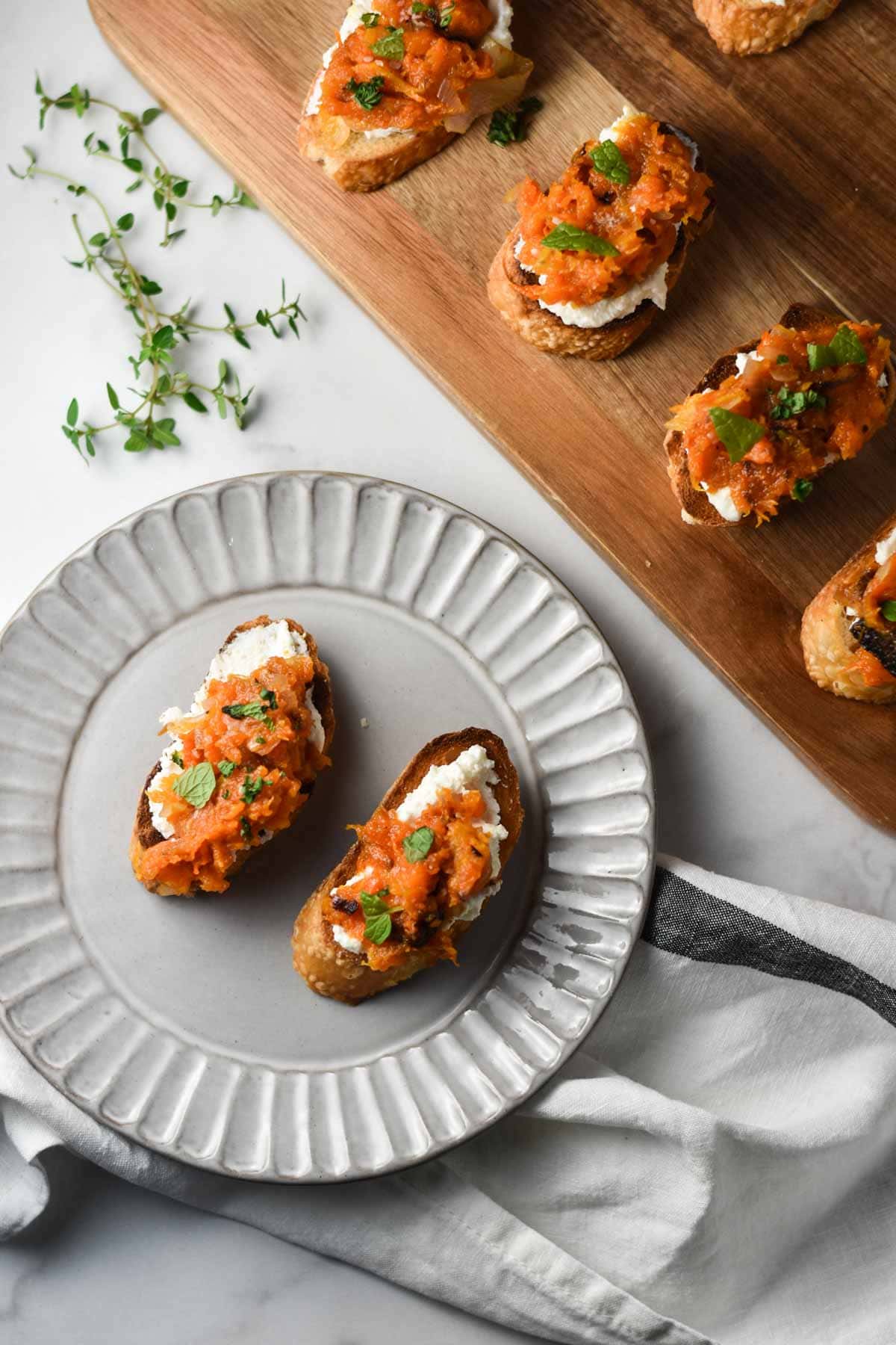 Two crostini topped with butternut squash on a grey plate.