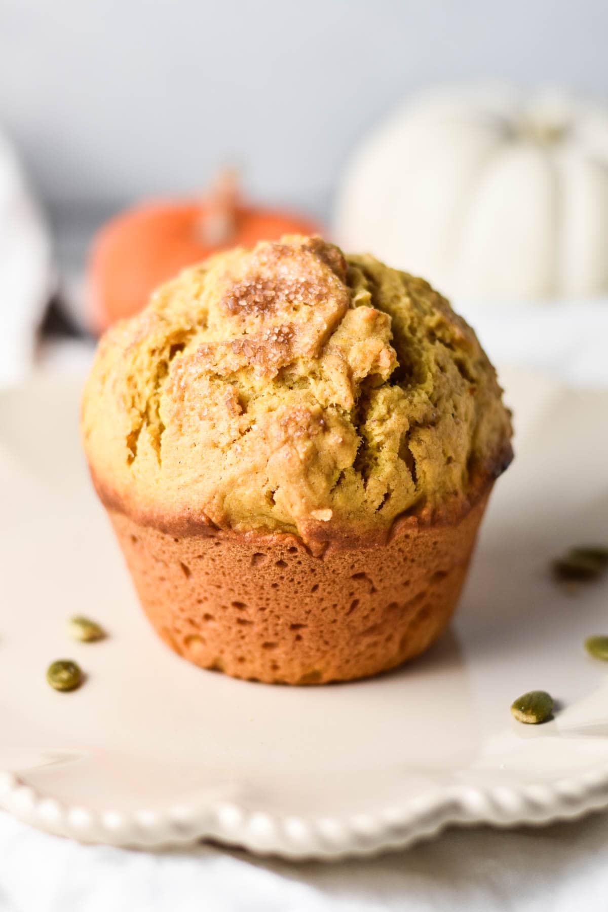 A large jumbo muffin on a plate with pepitas.