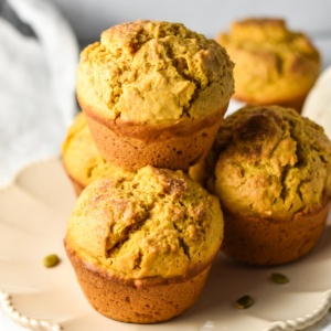 Pumpkin jumbo muffins stacked on a plate.