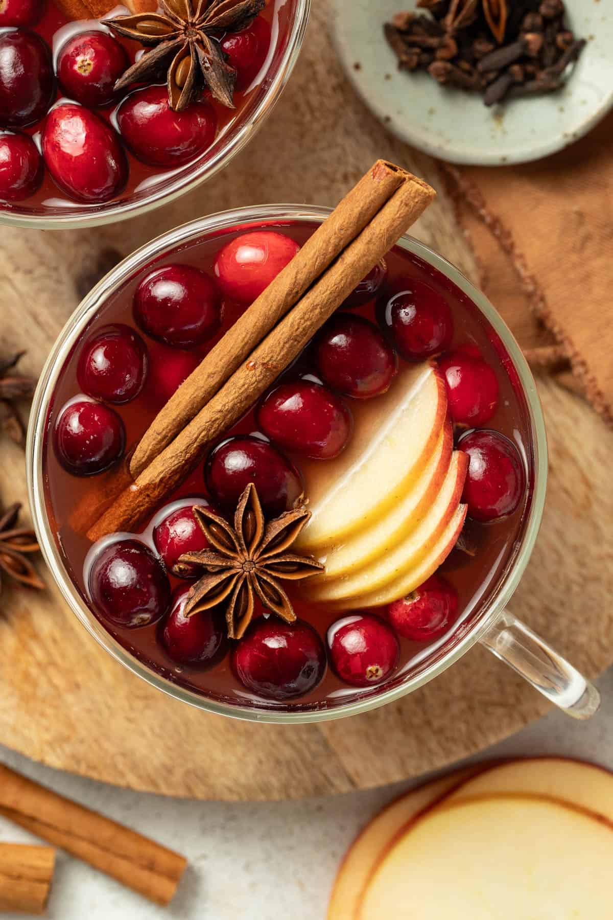 Wassail in a mug topped with fresh cranberries and star anise.