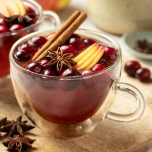 Two mugs of Christmas wassail next to cinnamon sticks and star anise.