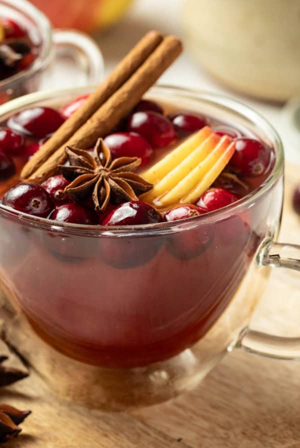 Two mugs of Christmas wassail next to cinnamon sticks and star anise.