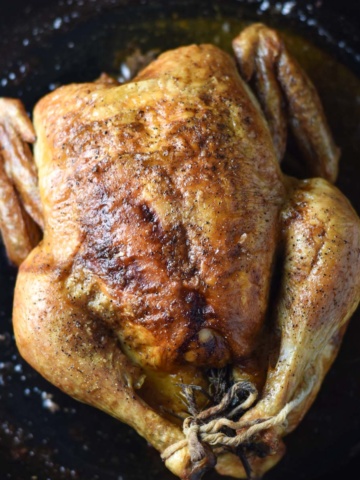 A roasted chicken in a cast iron pan.