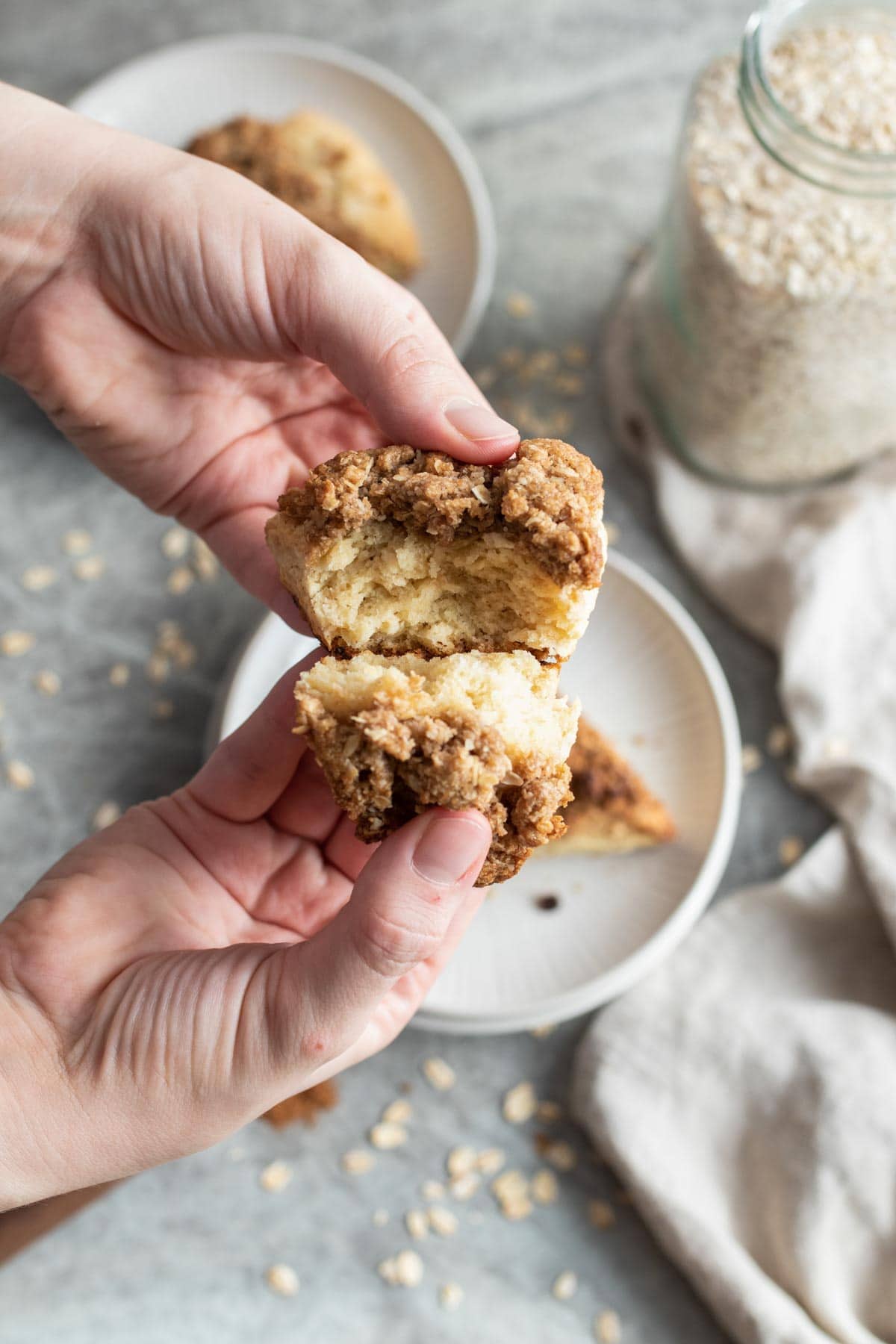 Hands breaking apart a scone with cinnamon crust.