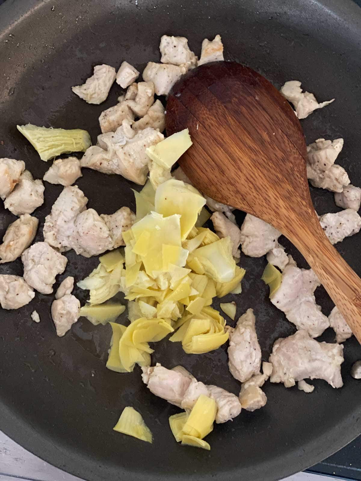 Cooking chicken and artichokes in a pan.