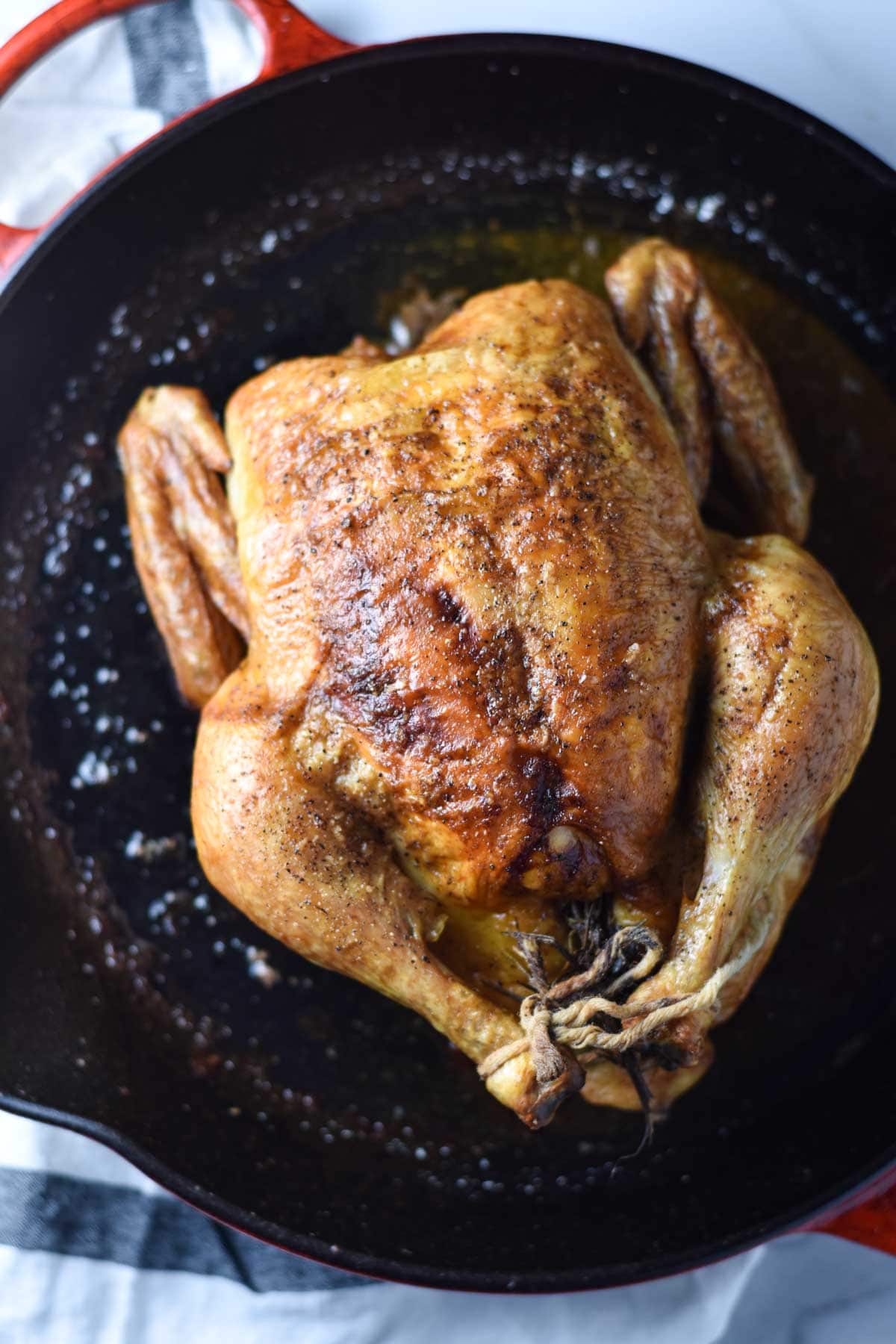 A whole roast chicken in a cast iron pan.