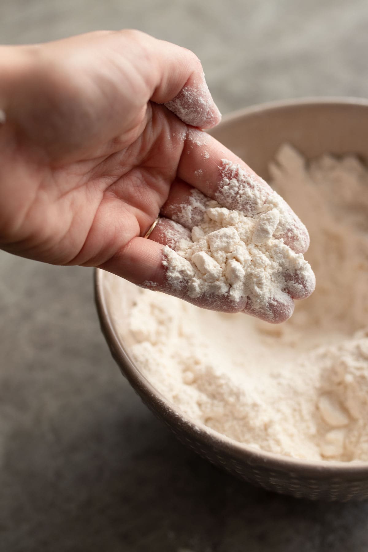 A hand showing how the flour for the scones should look crumbly.