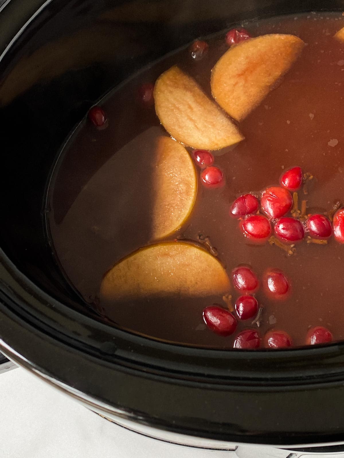 Apples, cranberries, and wassail in a slow cooker.