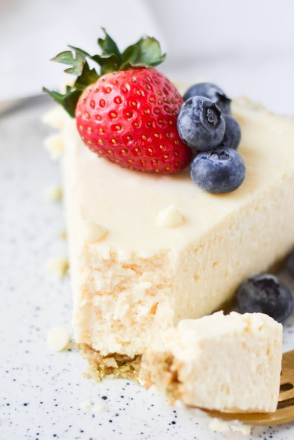 A white chocolate cheesecake slice with berries on top.