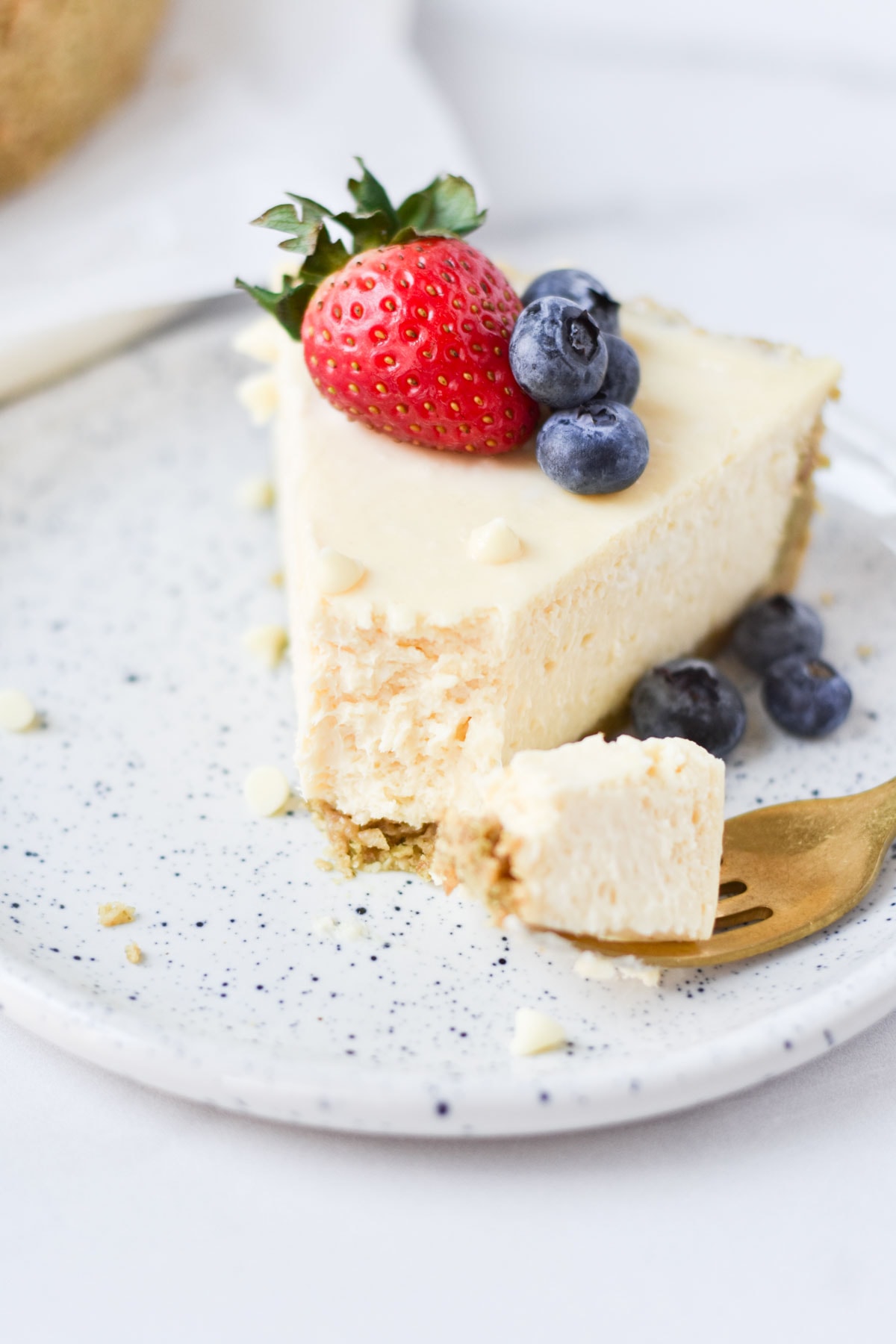 A bite of cheesecake with white chocolate and berries on top.