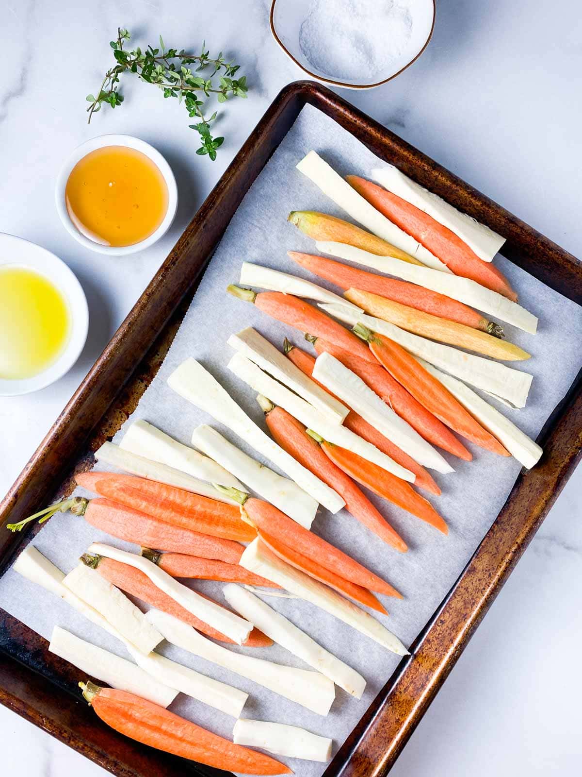 Cut carrots and parsnips next to honey and olive oil.