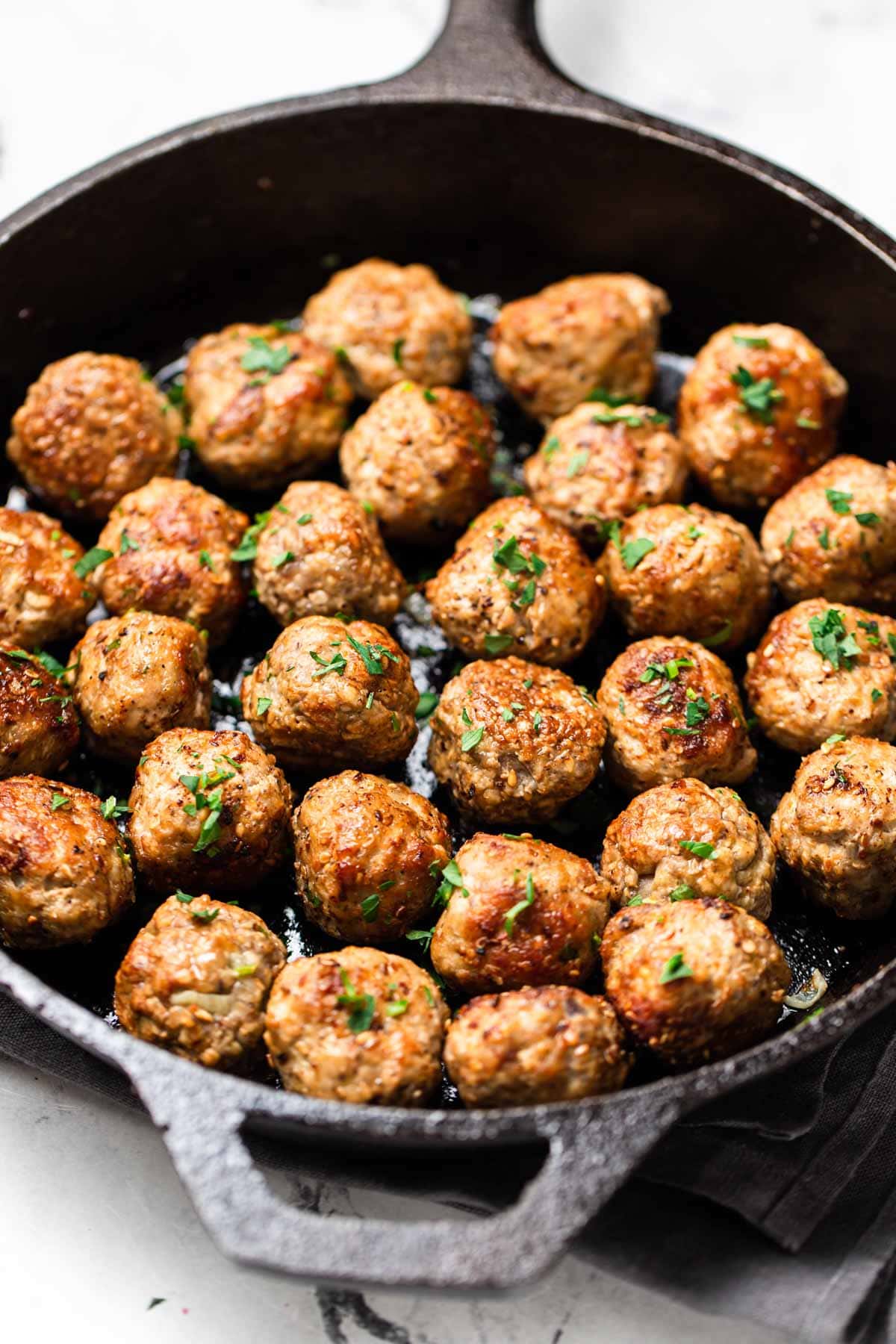 Cooked meatballs in a cast iron pan.