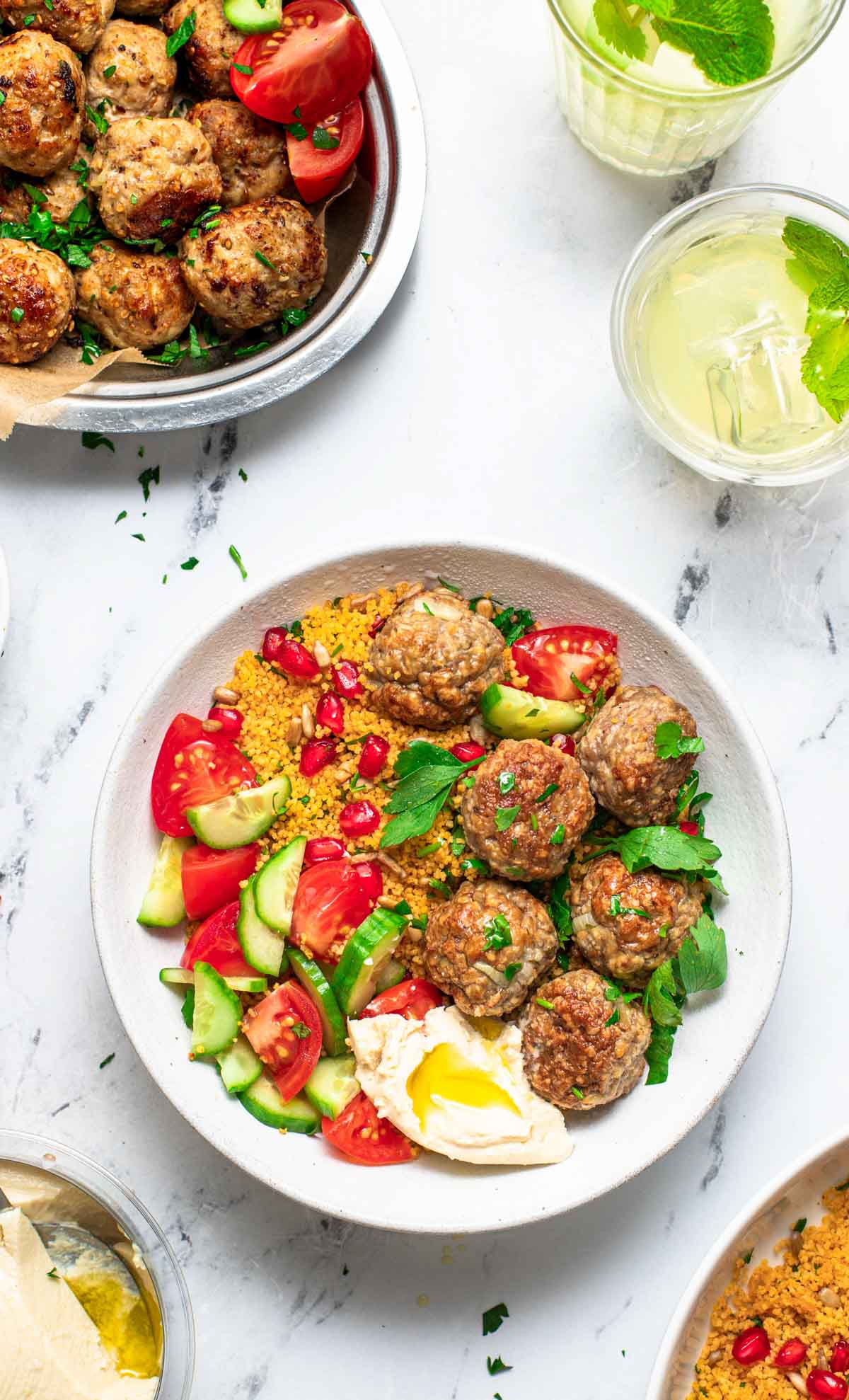 Meatballs with Mediterranean sides of hummus, cucumber, and tomatoes.