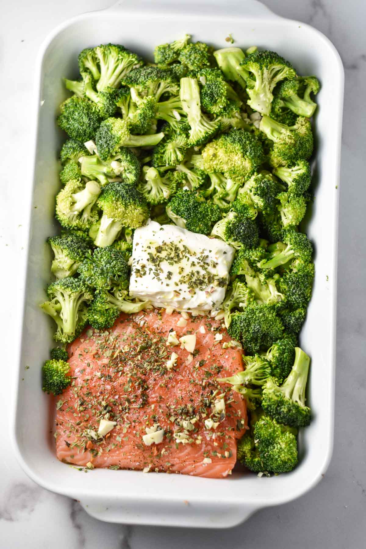 Salmon, broccoli, and cream cheese in a roasting pan before baking.
