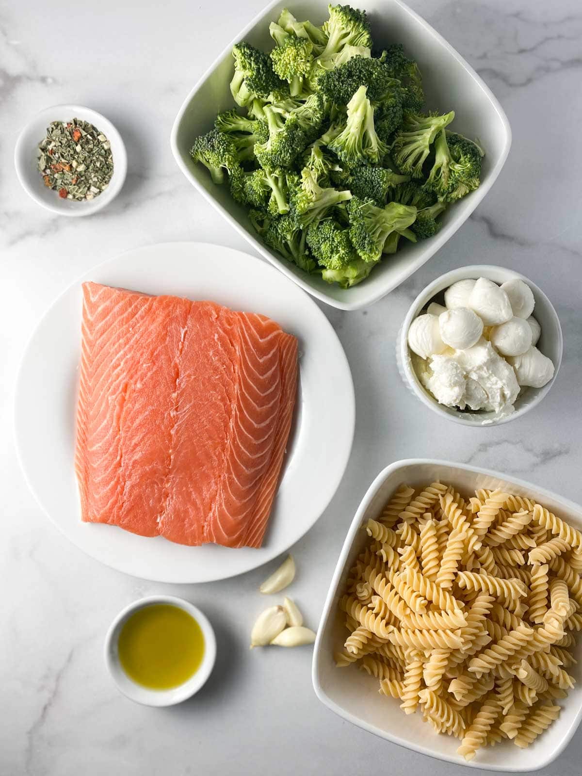 Ingredients for salmon broccoli pasta on a table.