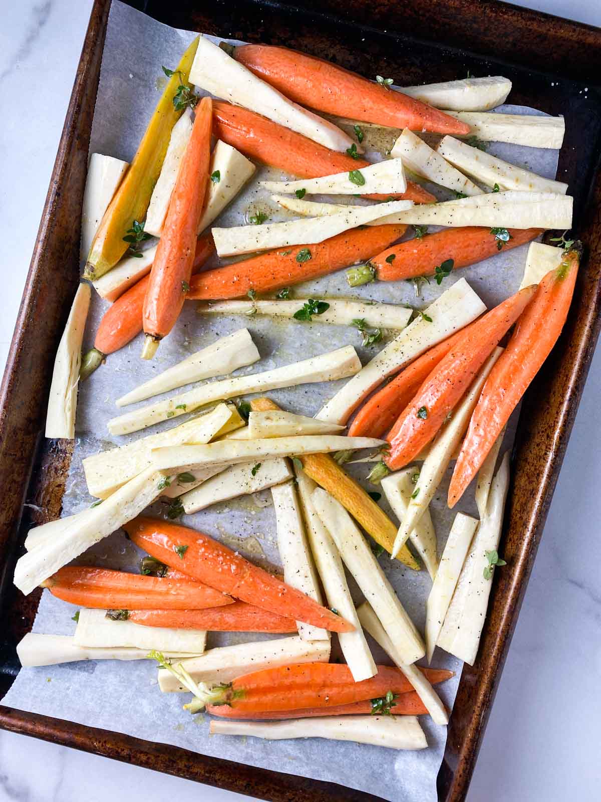 Cut carrots and parsnips on a roasting pan.