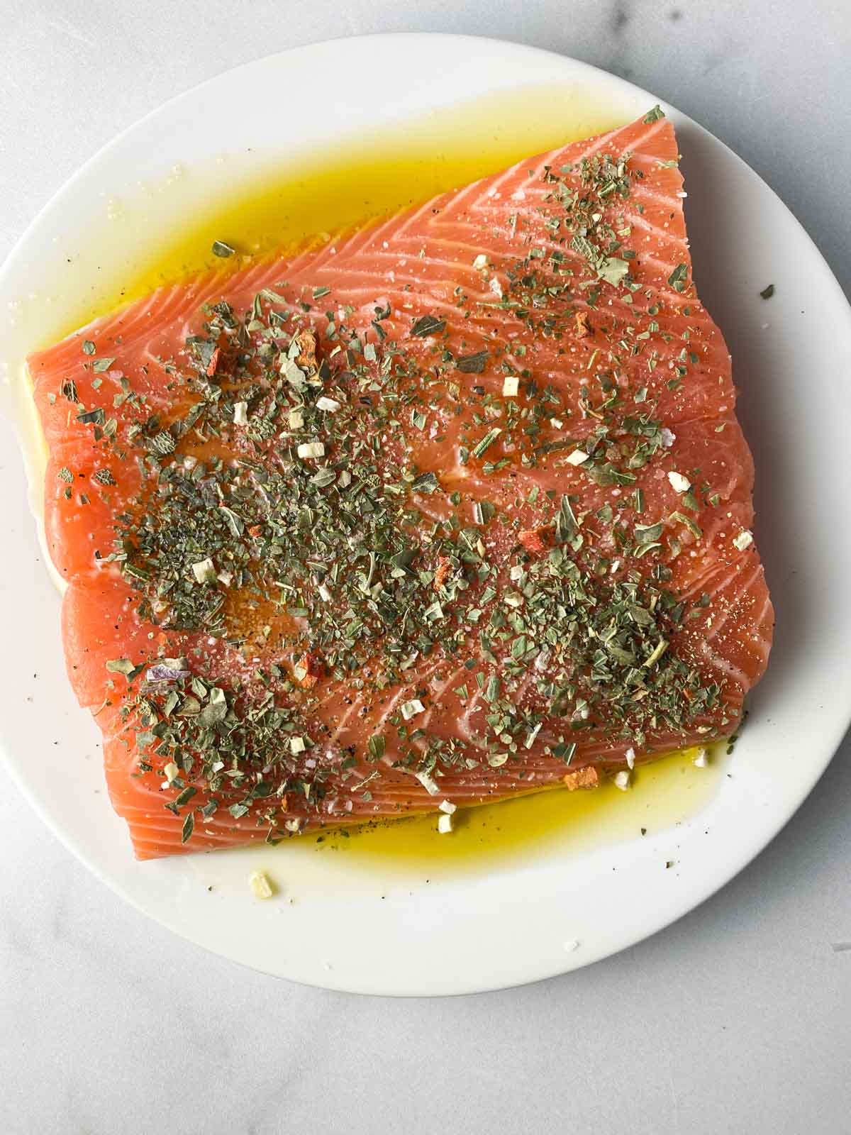 Salmon topped with Italian seasoning and olive oil.