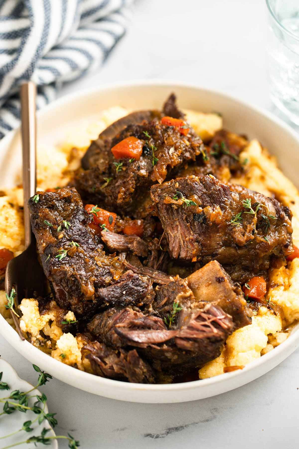 Short ribs on top of a creamy polenta in a bowl.
