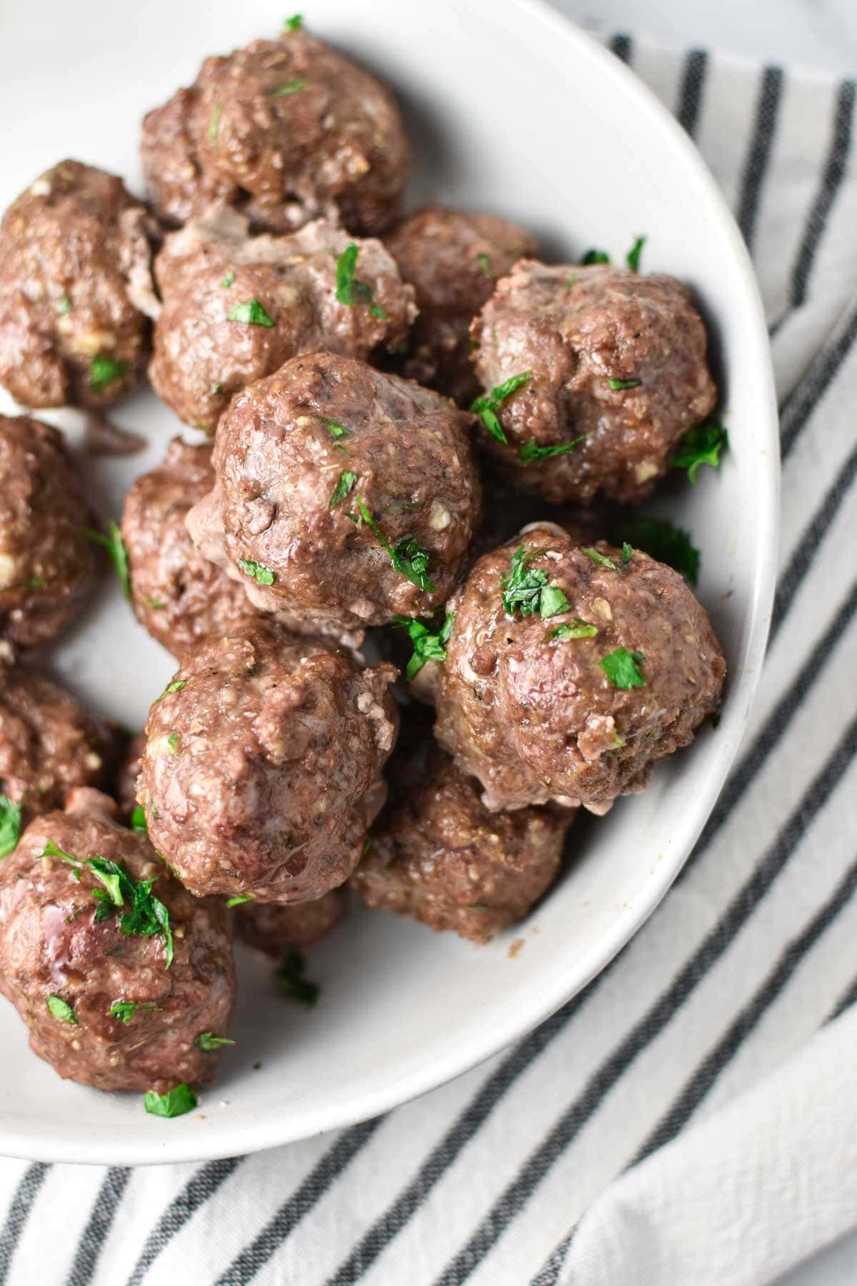 Cooked meatballs in a white bowl.