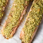 Three fillets of pepita crusted salmon on a baking sheet.