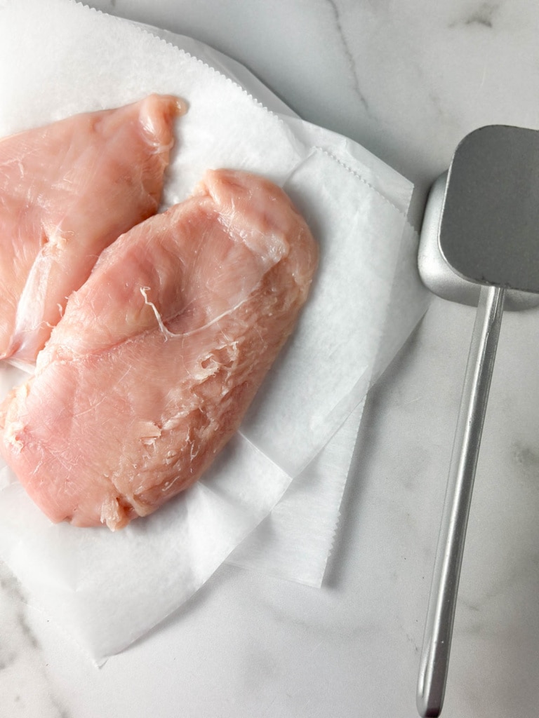 Pounding out raw chicken with a mallet.